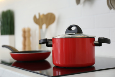Photo of Red pot and frying pan on stove in kitchen, closeup