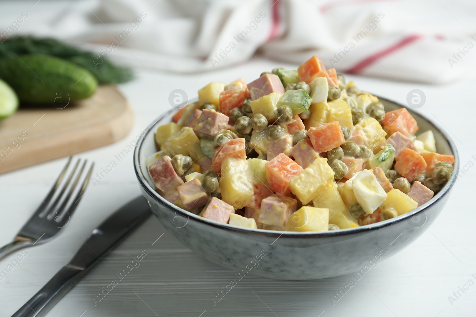 Photo of Delicious russian salad Olivier served on white wooden table