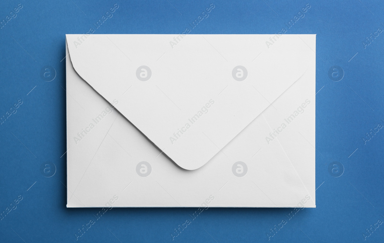 Photo of White paper envelope on blue background, top view