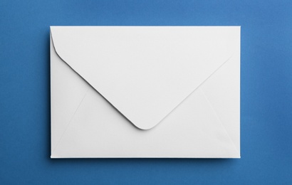 Photo of White paper envelope on blue background, top view