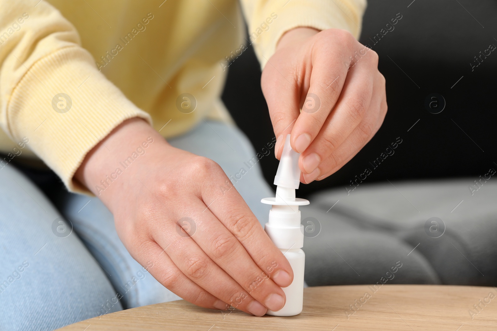 Photo of Woman with nasal spray at wooden table indoors, closeup