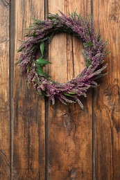Beautiful autumnal wreath with heather flowers on wooden background, top view. Space for text