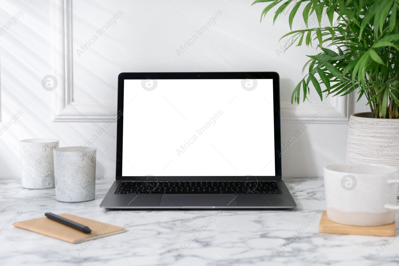 Photo of Office workplace with computer, glasses, cup and stationery on marble table near white wall