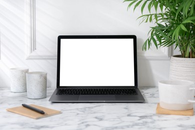 Photo of Office workplace with computer, glasses, cup and stationery on marble table near white wall