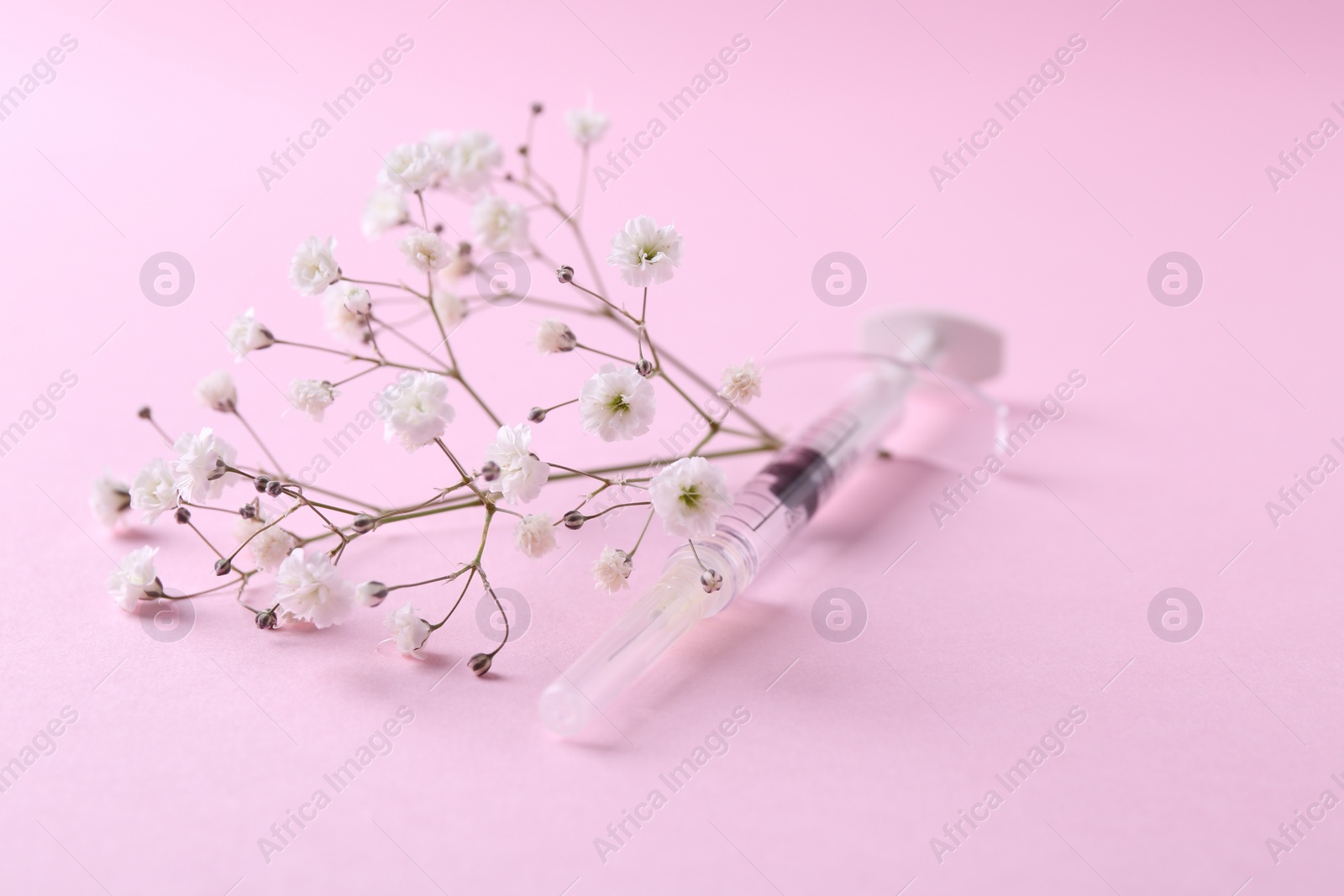 Photo of Cosmetology. Medical syringe and gypsophila on pink background, closeup