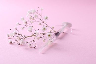 Cosmetology. Medical syringe and gypsophila on pink background, closeup