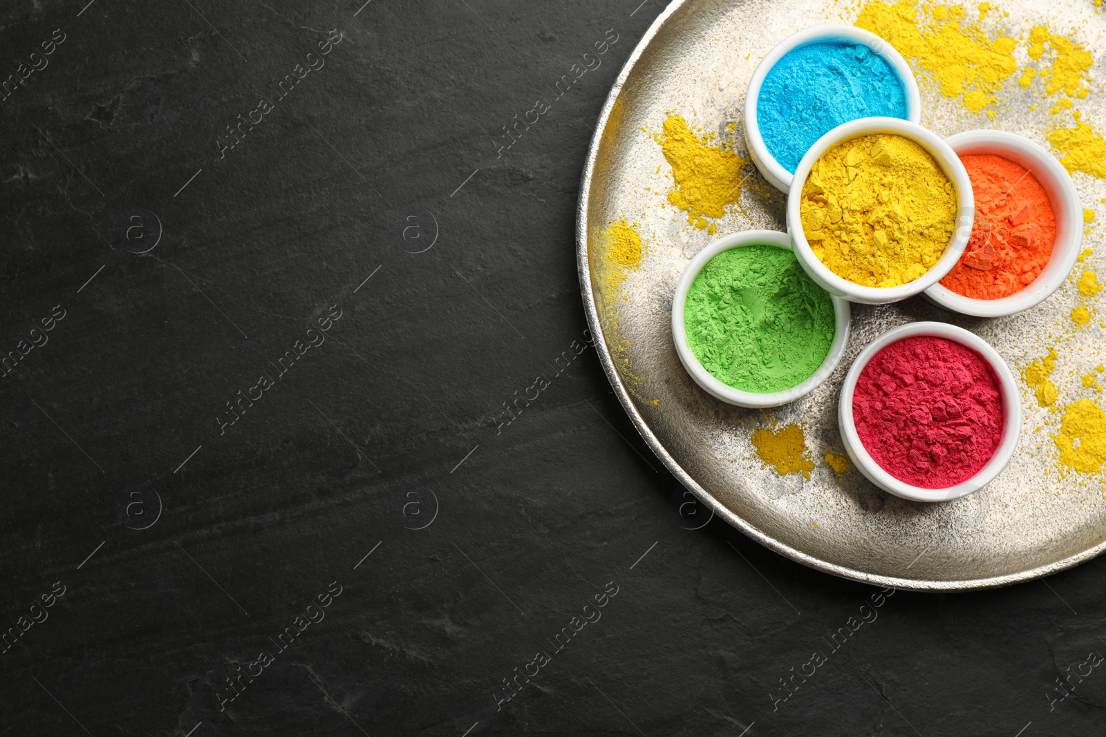 Photo of Colorful powder dyes on black background, top view with space for text. Holi festival