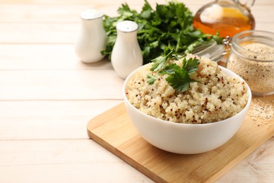 Photo of Tasty quinoa porridge with parsley in bowl on light table. Space for text