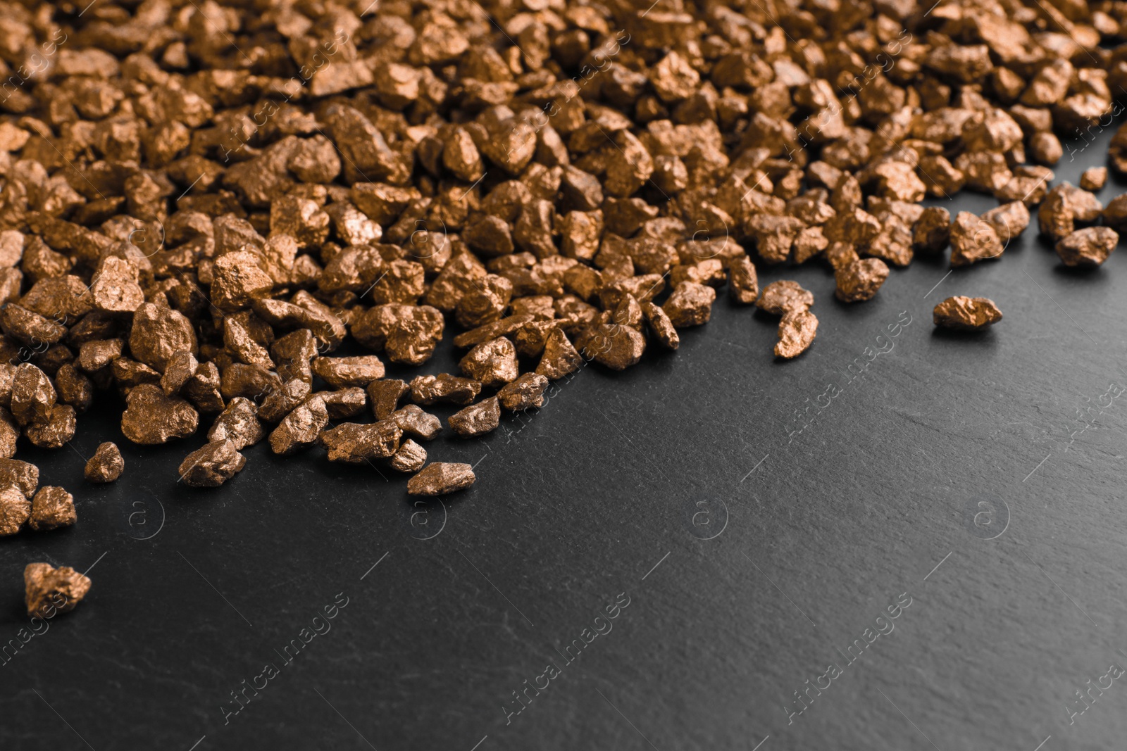 Photo of Pile of gold nuggets on black table. Space for text