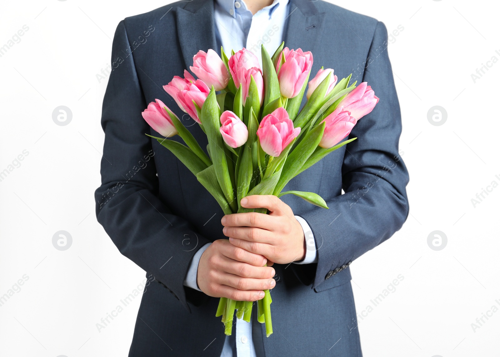 Photo of Man in elegant suit holding bouquet of beautiful spring tulips on light background, closeup. International Women's Day