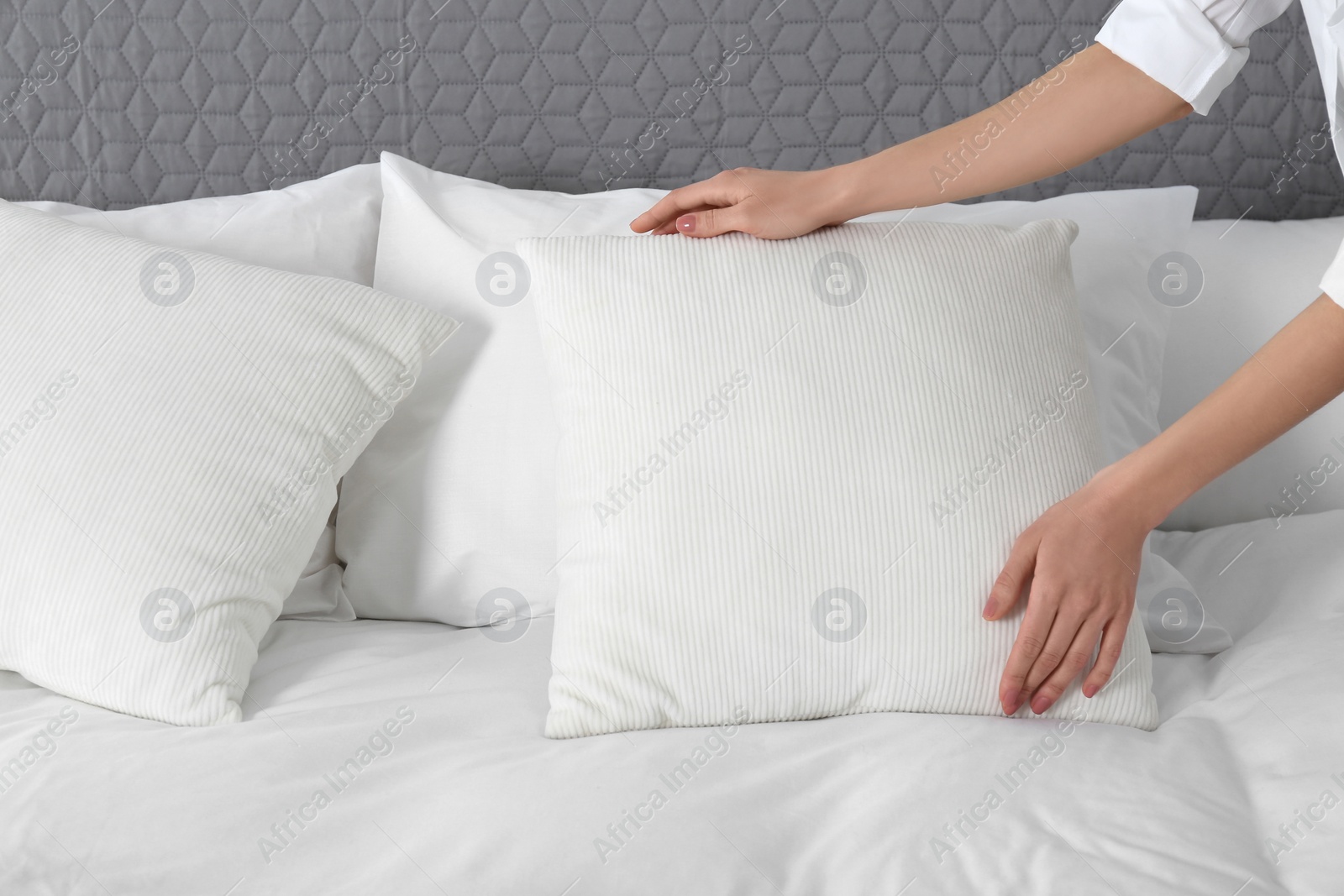 Photo of Woman fluffing soft pillow in bedroom, closeup