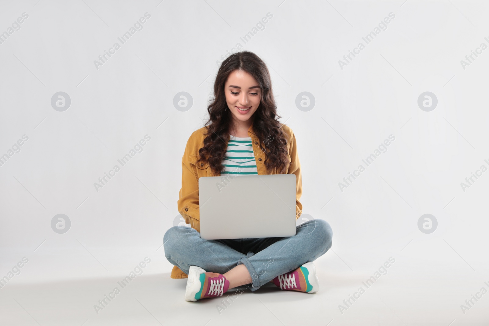 Photo of Young woman sitting with laptop on white background