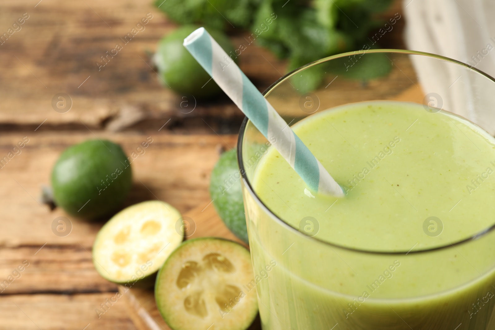 Photo of Fresh feijoa smoothie in glass on wooden table, closeup