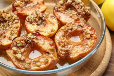 Tasty baked quinces with walnuts and honey in bowl on wooden table, closeup