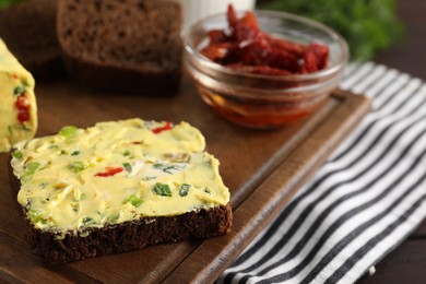 Photo of Tasty butter with green onion, chili pepper and rye bread on table, closeup