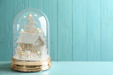 Photo of Beautiful snow globe on light blue wooden table, space for text