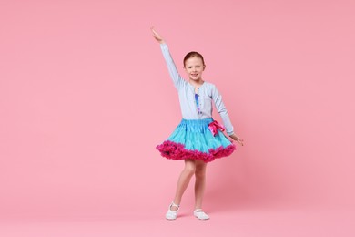 Photo of Cute little girl dancing on pink background