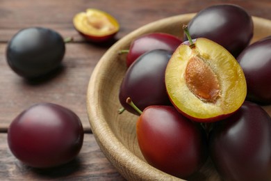 Photo of Tasty ripe plums on wooden table, closeup