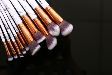 Photo of Set of makeup brushes on dark background, top view. Space for text