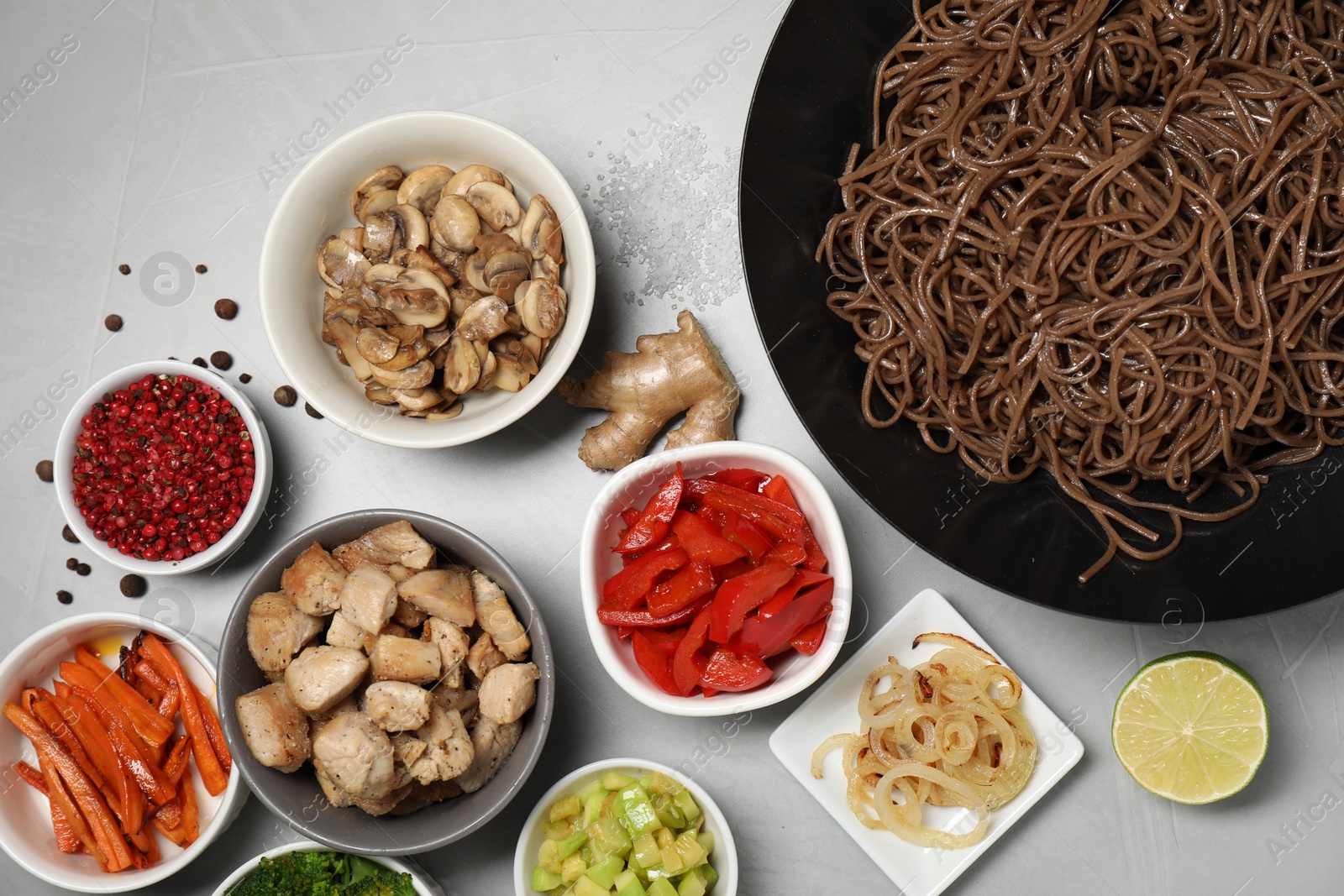 Photo of Wok with noodles, chicken and other products on light grey table, flat lay