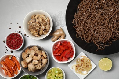 Photo of Wok with noodles, chicken and other products on light grey table, flat lay