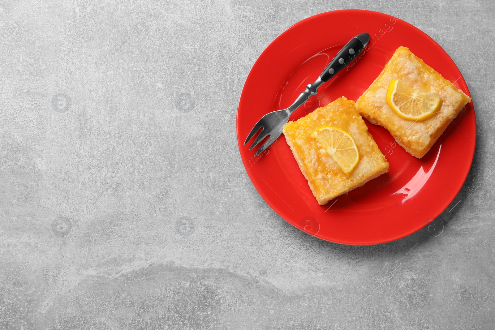 Photo of Tasty lemon bars and fork on light grey table, top view. Space for text