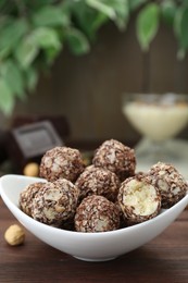 Photo of Bowl of delicious sweet chocolate candies on wooden table