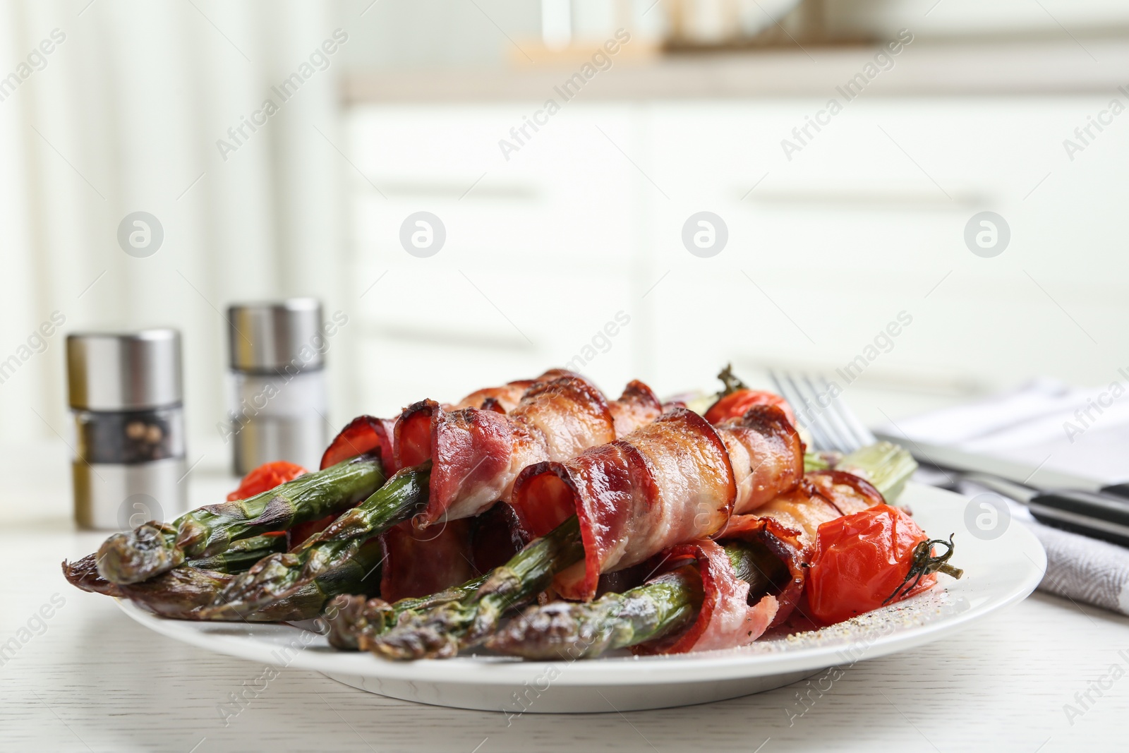 Photo of Oven baked asparagus wrapped with bacon on white wooden table