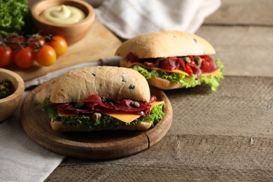 Photo of Delicious sandwiches with bresaola, lettuce and cheese on wooden table. Space for text