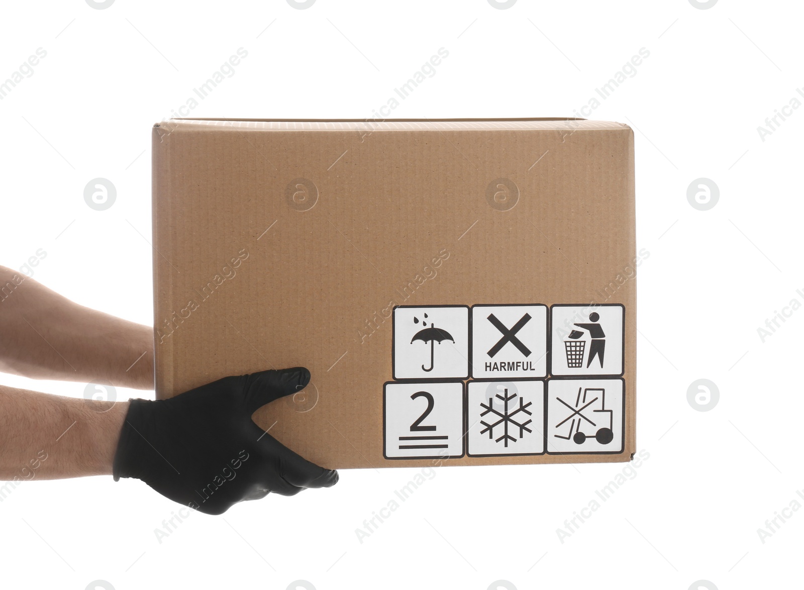 Photo of Courier holding cardboard box with different packaging symbols on white background, closeup. Parcel delivery