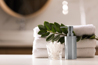 Composition with soap dispenser and towels on white table indoors