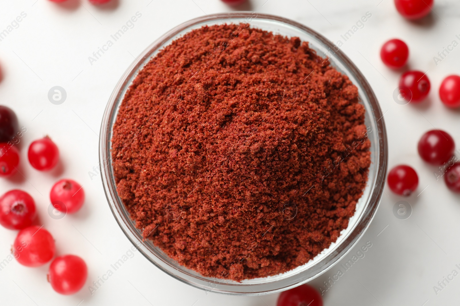 Photo of Dried cranberry powder in bowl and fresh berries on white table, top view