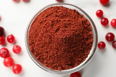 Dried cranberry powder in bowl and fresh berries on white table, top view