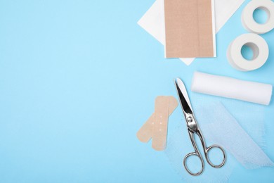 Photo of White bandage and medical supplies on light blue background, flat lay. Space for text