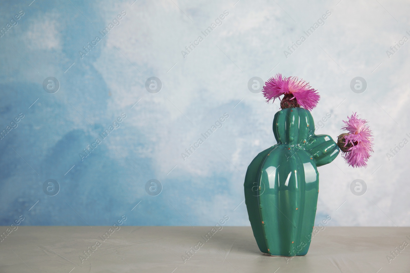 Photo of Trendy cactus shaped ceramic vase with flowers on table