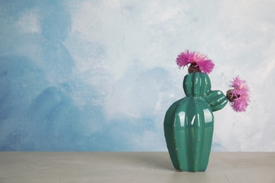 Trendy cactus shaped ceramic vase with flowers on table