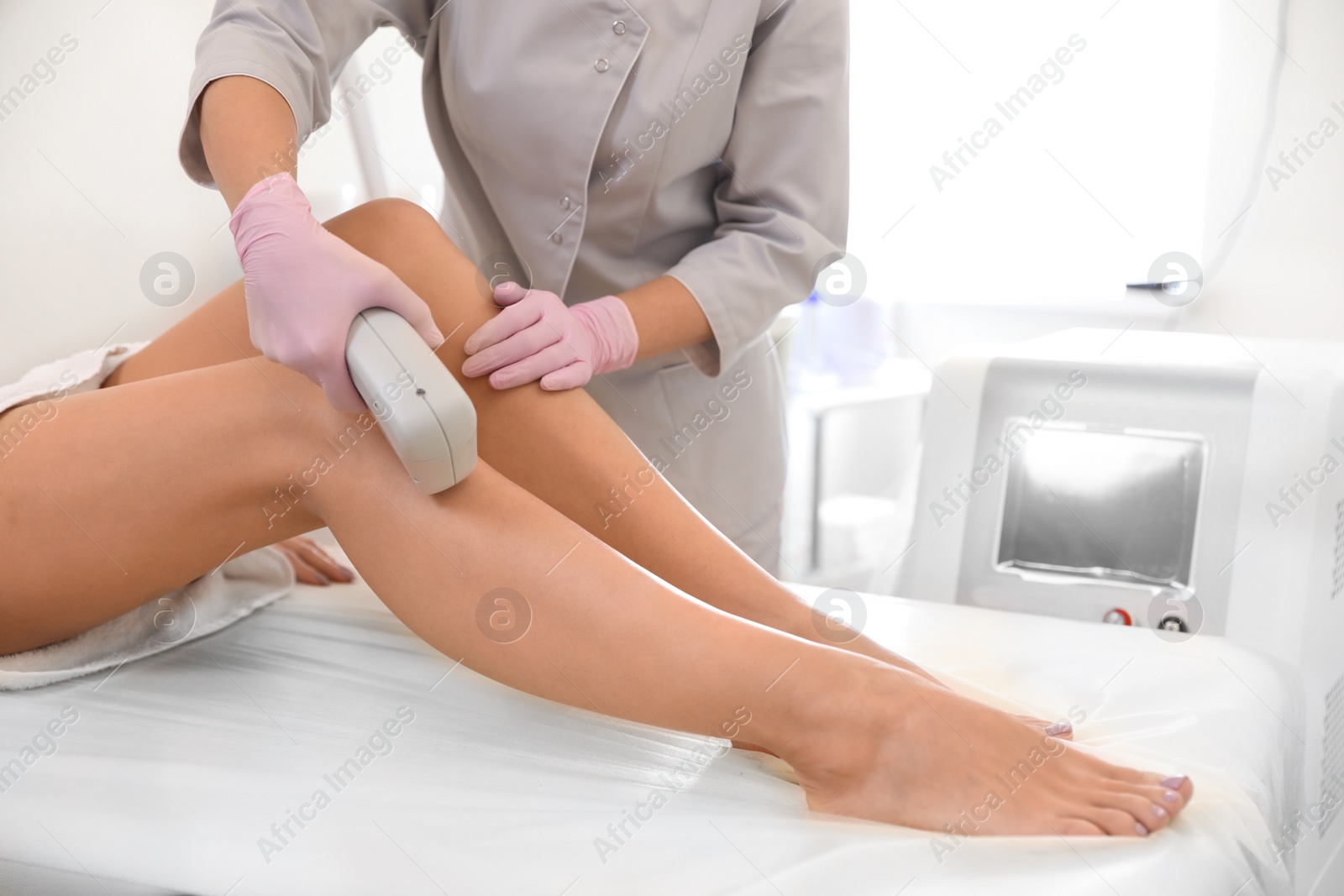 Photo of Young woman undergoing laser epilation procedure in beauty salon, closeup