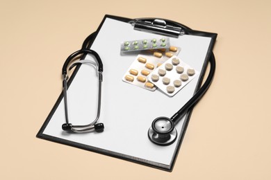 Stethoscope, pills and clipboard on beige background. Medical tool