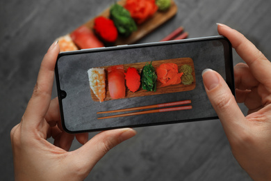 Photo of Blogger taking photo of sushi set at grey table, closeup