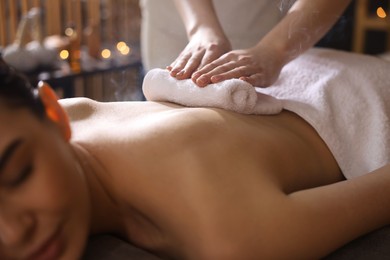 Photo of Spa therapy. Beautiful young woman lying on table during hot towel massage in salon, closeup