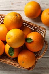 Many ripe oranges and green leaves on wooden table, top view