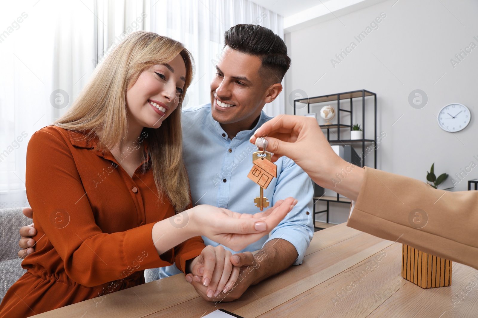 Photo of Real estate agent giving house key to couple at table in office