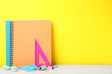 Photo of Different school stationery on white table against yellow background, space for text. Back to school