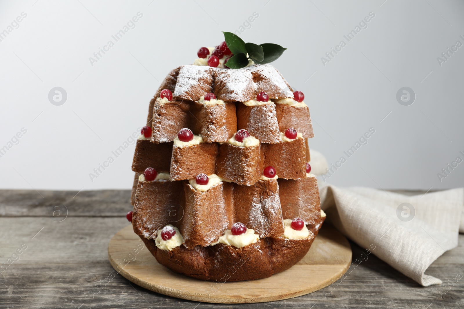 Photo of Delicious Pandoro Christmas tree cake with powdered sugar and berries on wooden table