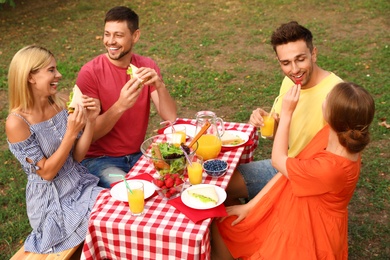 Group of people having picnic at table in park on summer day