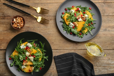 Photo of Delicious persimmon salad with pomegranate and arugula served on wooden table, flat lay
