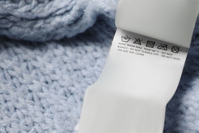 Photo of Clothing label on light blue garment, closeup. Space for text