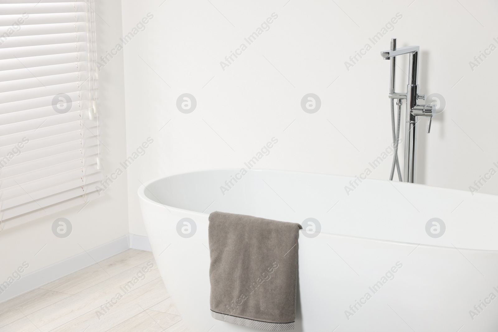 Photo of Stylish bathroom interior with ceramic tub and terry towel