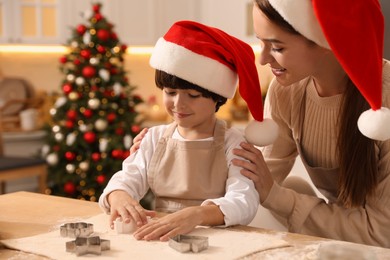 Photo of Mother with her cute little son making Christmas cookies in kitchen