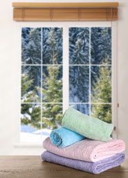 Image of Fresh towels on wooden table and window with beautiful view indoors